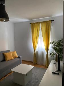 ein Wohnzimmer mit Sofa und gelben Vorhängen in der Unterkunft Tranquilo piso en Cimadevilla in Gijón