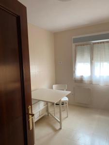 Zimmer mit einem Tisch, einem Stuhl und einem Fenster in der Unterkunft Tranquilo piso en Cimadevilla in Gijón