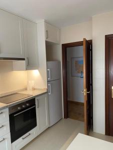 eine Küche mit weißen Schränken und einem Kühlschrank in der Unterkunft Tranquilo piso en Cimadevilla in Gijón