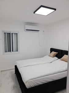 um quarto branco com uma cama e uma janela em דירת נופש em Tiberias
