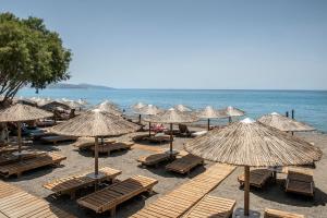 a beach with chairs and umbrellas and the ocean at Dione Villa in Kókkinos Pírgos