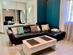 a living room with a black leather couch and a table at Magnifique villa in Dieupentale