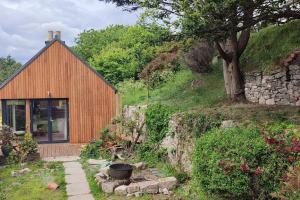 a wooden house with a tree and a stone wall at Stonehaven 2 Bedroom Seaside Cottage with Garden in Stonehaven