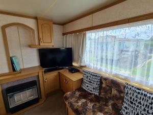 een woonkamer met een bank, een tv en een raam bij Hemsby Caravan Hire in Hemsby