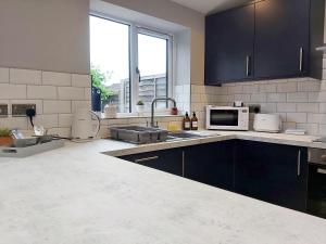 a kitchen with a sink and a microwave at Modern 4 Bedroom House with Parking in Wyken