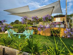 a garden with purple flowers and a white umbrella at al pie de las sierras en villa del lago in Tandil