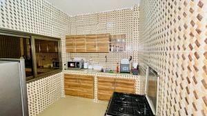La cuisine est équipée de placards en bois et d'un four avec plaques de cuisson. dans l'établissement JIKKE Appartement, à Dakar