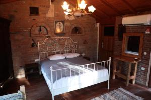 um quarto com uma cama branca numa parede de tijolos em Kayserkaya Cottages em Selçuk