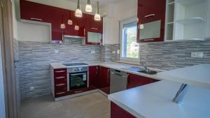 a kitchen with red cabinets and a stove top oven at Casa llena in Seget Vranjica