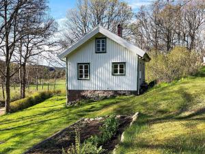 una pequeña casa blanca en una colina de hierba en Holiday home BRASTAD XV, en Brastad
