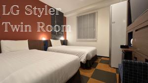 a hotel room with two beds and a tv at Henn na Hotel Tokyo Haneda in Tokyo