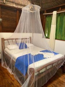 a bed covered with a net in a room at Casa de la Iguana in Lívingston