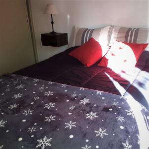 Cama con almohadas rojas y manta con copos de nieve en Departamento FAMILY en Mendoza