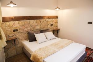 Ce lit se trouve dans un dortoir doté d'un mur en pierre. dans l'établissement Issli appartment, à Azrou