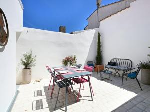 un patio con tavolo, sedie e parete bianca. di Maison Les Portes-en-Ré, 3 pièces, 4 personnes - FR-1-434-98 a Les Portes