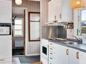 una cocina con armarios blancos y fregadero en Holiday home Hemmet CCXLIV en Hemmet