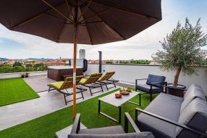 a patio with chairs and an umbrella on a roof at PANORAMA DELUXE APARTMENT in Zadar