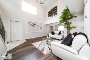 a living room with white furniture and a palm tree at LUXURIOUS 6 Bed Home I Fireplace I near Sports Park I with Double Garage & Fast WiFi! in Edmonton