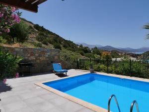 una piscina con una silla junto a una montaña en Istron Collection Villas, Villa Selini, en Istron