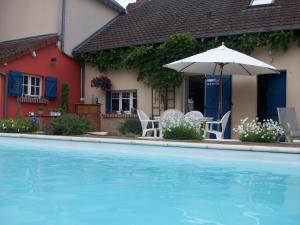 a house with a pool and an umbrella and chairs at Loire, Châteaux, et Vignes in Onzain