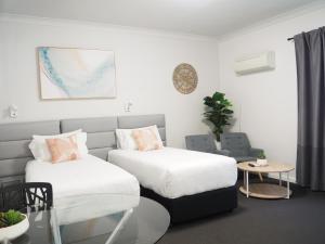 uma sala de estar com duas camas e um sofá em The Esplanade Motel em Warners Bay