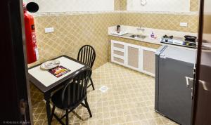 a small kitchen with a table and chairs and a refrigerator at Al Jumhour Hotel Apartments in Sur