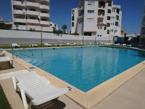uma grande piscina com um banco branco e alguns edifícios em 1 Bedroom Apartment Chaves, Praceta Vitorino Nemesio, Albufeira em Albufeira