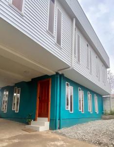 un edificio azul con una puerta roja y ventanas en Hostal Ejecutivo, en Victoria