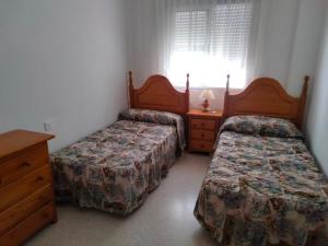 1 dormitorio con 2 camas, vestidor y ventana en Pisos Isla Cristina 2, en Isla Cristina