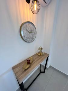 a clock on a wall next to a wooden table at Rothschild Royal in Ashdod