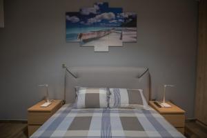 ein Schlafzimmer mit einem Bett mit zwei Nachttischen und zwei Lampen in der Unterkunft Max Blue apartment, a stay like no other in Piräus