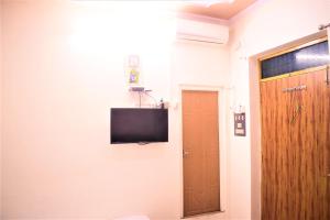 a room with a tv on the wall and a door at DS Residency-Near Varanasi Jn Railway station N Temples-Parking-Free Wi-Fi in Varanasi