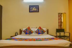 1 dormitorio con 1 cama grande y almohadas coloridas en FabHotel Hibiscus Stays, en Chennai