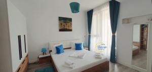 - une chambre avec un lit blanc et des oreillers bleus dans l'établissement Onix Bluescape, à Mamaia Nord – Năvodari