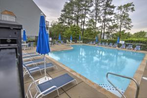 a swimming pool with chairs and blue umbrellas at 34 Pier Point Dr in Millville