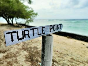 a street sign on a pole on the beach at Gili Mesari Cottages & Homestay in Gili Trawangan