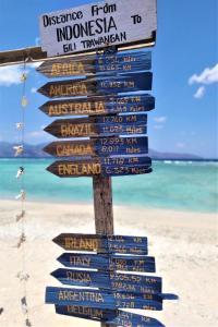 a sign on the beach with many different signs at Gili Mesari Cottages & Homestay in Gili Trawangan