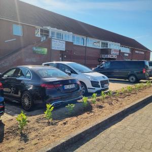 zwei Autos auf einem Parkplatz vor einem Gebäude geparkt in der Unterkunft Müritz-Pension Waren in Waren (Müritz)