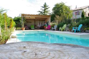 uma piscina num quintal com cadeiras coloridas e um quintal em Maison d'Hôtes Lou Cliou em Cliousclat