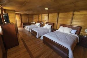 Habitación con 2 camas, paredes de madera y suelo de madera. en Quinta Spa El Rosal en Ambato