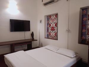 a bedroom with two beds and a tv and a table at 5/4 - Calcutta's freshest BnB in Kolkata