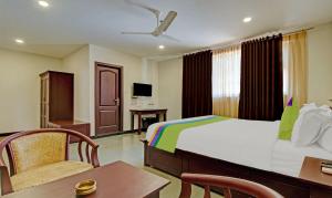 Una habitación de hotel con una cama, una mesa y sillas. en Treebo Prince, en Kottayam