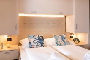 a bedroom with a white bed with blue and white pillows at Mara's Coast - Giulia in Drage