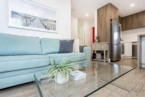 a living room with a blue couch and a kitchen at Cottesloe Beach View Apartment - EXECUTIVE ESCAPES in Perth