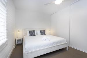 a white bedroom with a white bed and a window at Cottesloe Beach View Apartment - EXECUTIVE ESCAPES in Perth