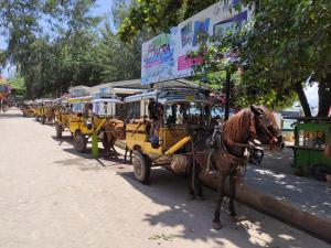 a horse pulling a line of yellow carriages at Gili Mesari Cottages & Homestay in Gili Trawangan