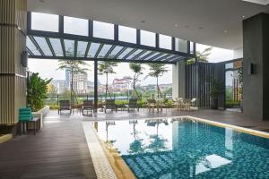 a swimming pool with tables and chairs in a building at Hotel Komune Living & Wellness Kuala Lumpur in Kuala Lumpur