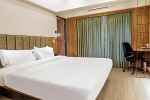a hotel room with a bed and a desk at Hotel Olten in Mumbai