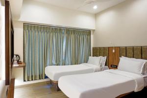 a hotel room with two beds and a window at Hotel Olten in Mumbai