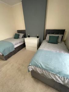um quarto com 2 camas individuais e uma mesa de cabeceira em Bentley Place em Crewe